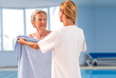 caregiver giving towel to a senior woman