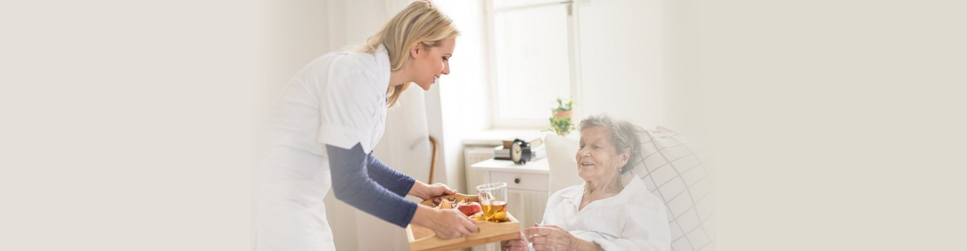 caregiver giving food to senior woman