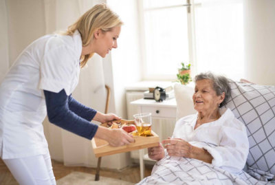 caregiver giving food to a senior woman
