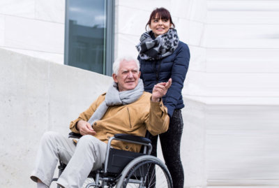 caregiver together with senior man on wheelchair